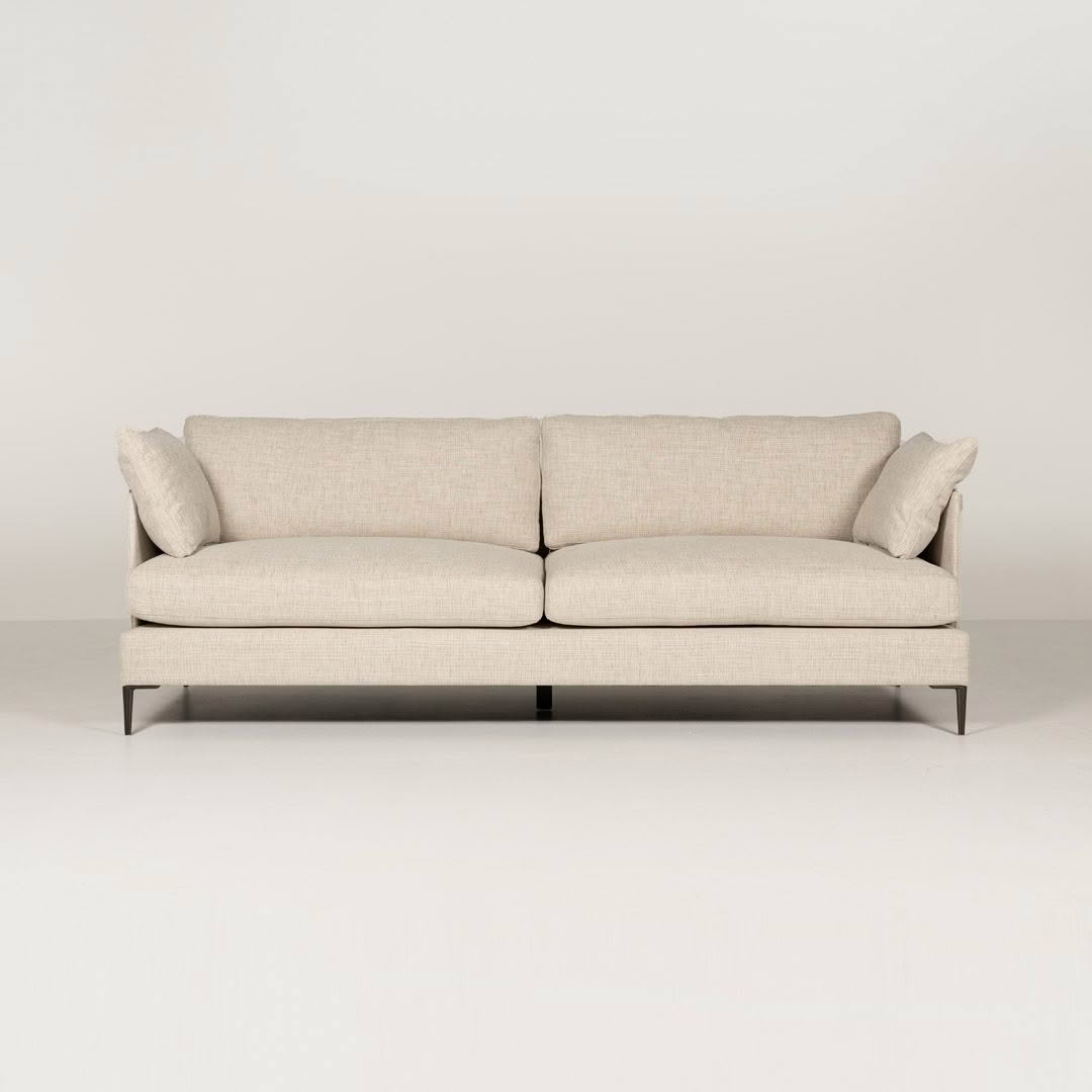 Modern beige sofa with cushions on white background