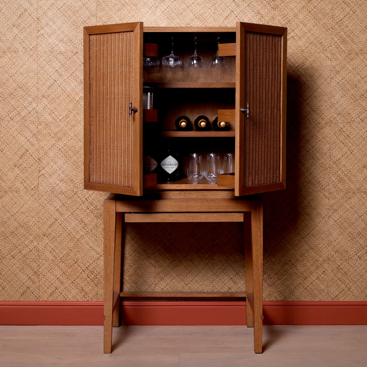 Elegant wooden bar cabinet with open doors displaying bottles and glasses.