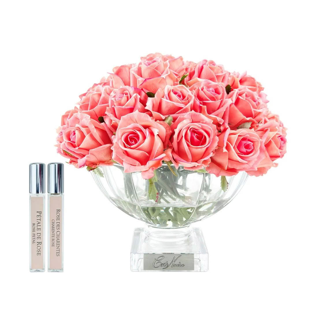 Pink roses in vase with floral perfume bottles