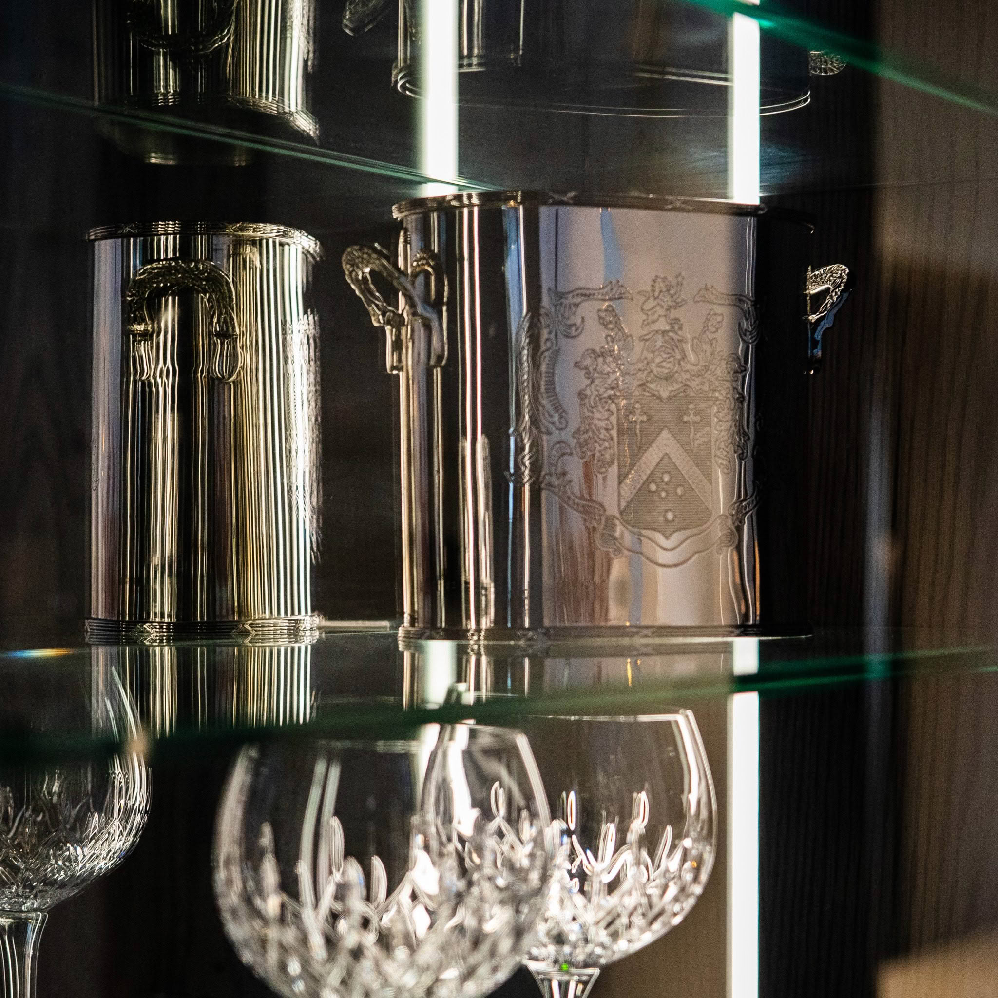 Elegant engraved silver tankards and crystal glasses on shelves