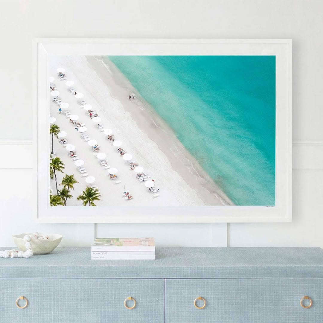 Aerial view of beach with umbrellas and clear blue water.